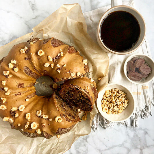 Milk chocolate, spice and coffee cake with espresso glaze and roasted hazelnuts ready to serve