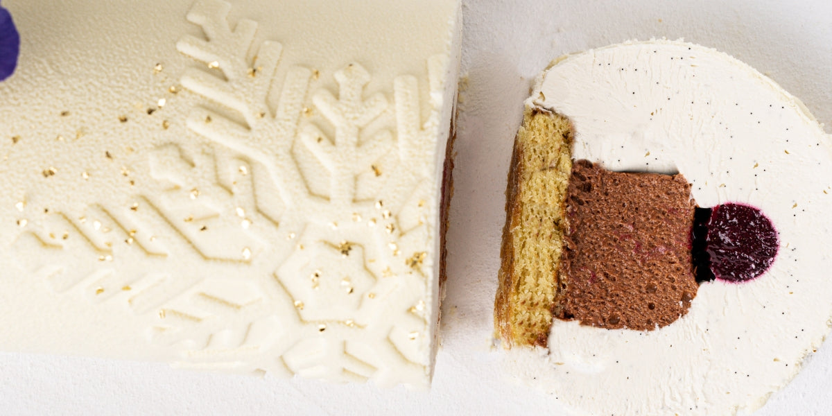 Ivoire and blackcurrant Christmas yule log featuring white chocolate whipped ganache and a smooth velvet texture.