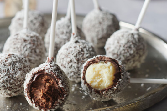 Dark Chocolate Cake Pops placed on a clear plate and cut in the middle to see the coconut praline inside