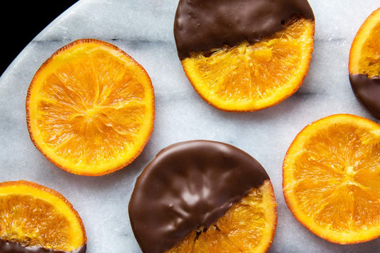 Dark chocolate dipped candied orange peel snacks displayed on parchment paper