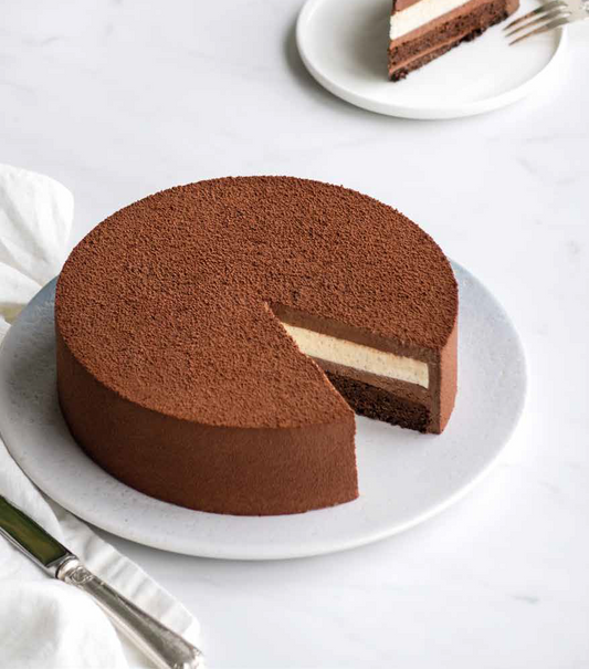 Dark and white chocolate layer cake ready to be served with a slice on the side