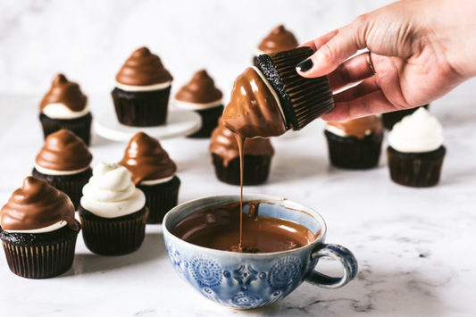 Dark chocolate cupcakes with a milk chocolate shell, being dipped in chocolate