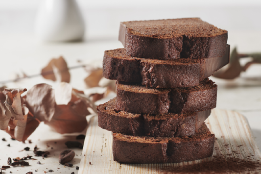 Dark chocolate gluten-free cake cut in slices and stacked on top of each other on a wooden board