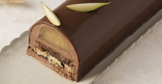 Dark Chocolate, Pear and Cookie Yule Log presented on a rectangle plate and cut to see the layers inside