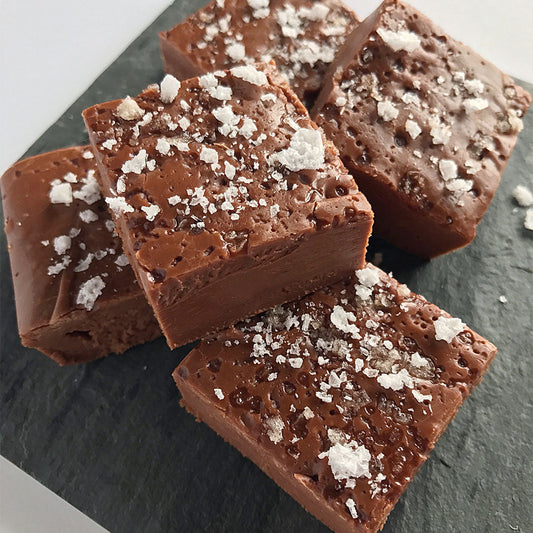 Dark chocolate salted fudge cut in squares and stacked on top of each other