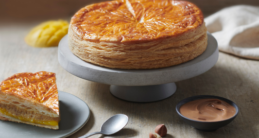 Praline king cake with nutty vanilla cream and mango compote displayed on a table