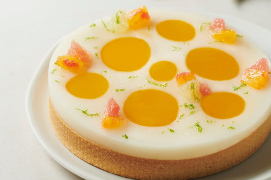 A vibrant citrus tart topped with passion fruit crémeux, eggless lemon meringue, and fresh citrus segments on a golden shortbread crust.