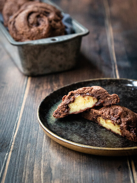 Dark chocolate chip cookies with vanilla cream displayed in a plate and cut in half